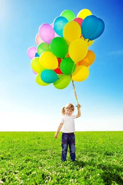 Niña sosteniendo globos de colores. Niño jugando en un verde — Foto de Stock