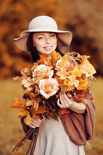 Jeune femme de mode marchant dans le parc d'automne avec un bouquet de fa — Photo