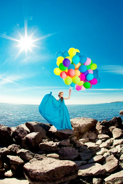 Luxusmode Frau mit Luftballons in der Hand am Strand gegen — Stockfoto