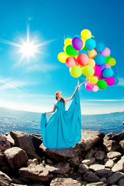 Luxusmode Frau mit Luftballons in der Hand am Strand gegen — Stockfoto