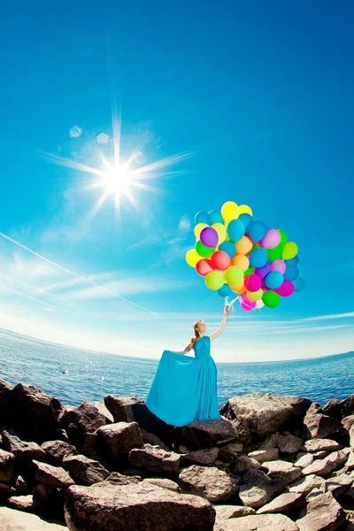 Luxe mode vrouw met ballonnen in de hand op het strand tegen — Stockfoto