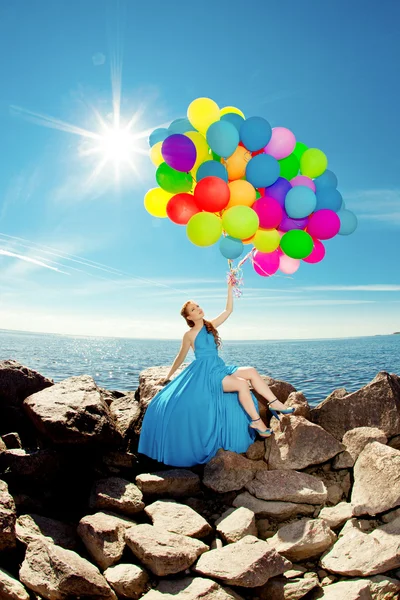 Lyx mode kvinna med ballonger i handen på stranden mot — Stockfoto