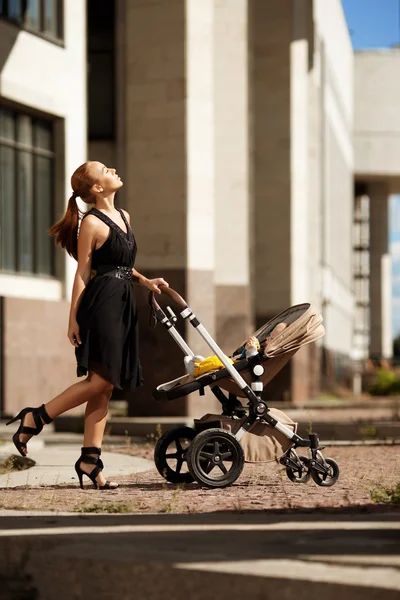 时尚现代的母亲在街头与一辆婴儿车。年轻的莫 — 图库照片