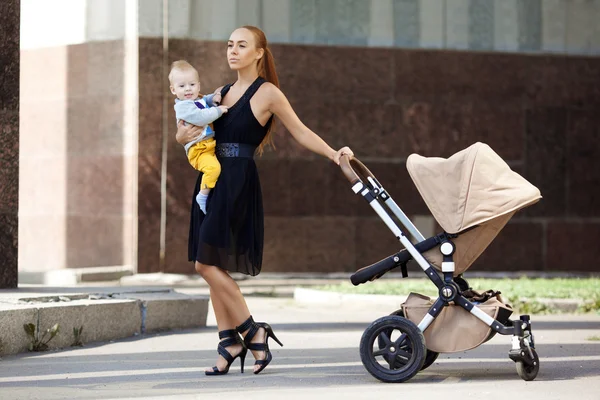 Trendy modern mother on a city street with a pram. Young mother — Stock Photo, Image