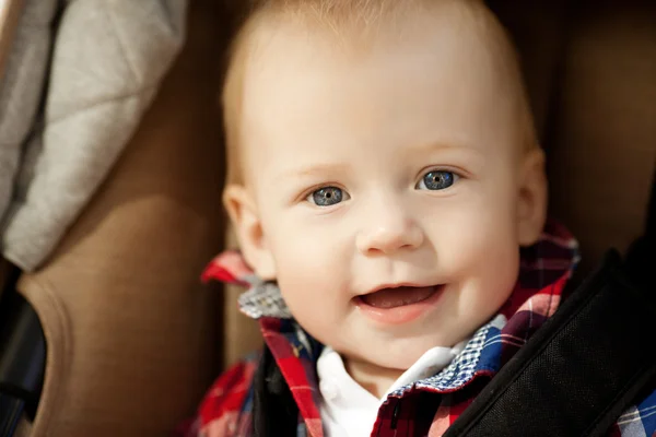 Mooie kleine glimlachende baby in een kinderwagen op de straten — Stockfoto