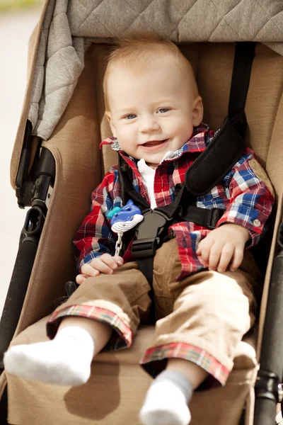 Schattige kleine glimlachende baby in een kinderwagen op de straten van th — Stockfoto