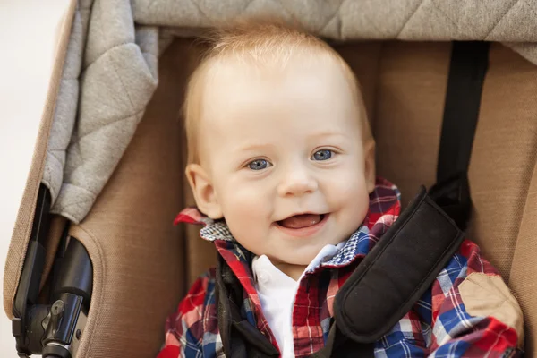 Mignon petit bébé souriant dans une voiture de bébé dans les rues de th — Photo