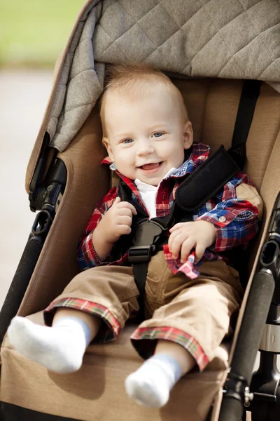 Bebê sorridente bonito em uma carruagem de bebê nas ruas — Fotografia de Stock