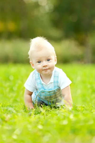 Schattige kleine baby in het park op het gras. zoete baby buitenshuis. lachende emotionele kind op een vrije loop. glimlach van een kind — Stockfoto