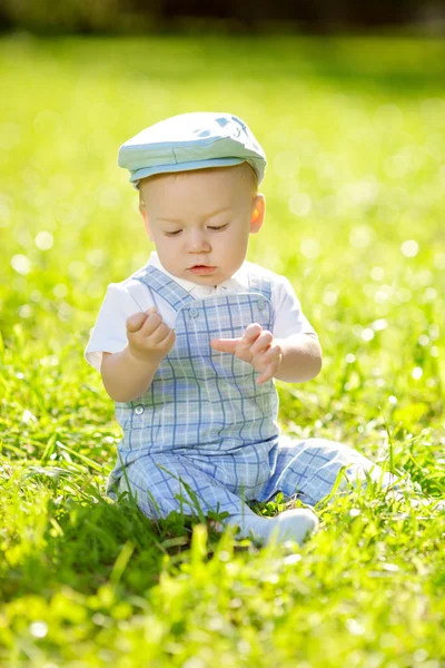 Schattige kleine baby in het park op het gras. zoete baby buitenshuis. lachende emotionele kind op een vrije loop. glimlach van een kind — Stockfoto