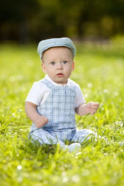 Schattige kleine baby in het park op het gras. zoete baby buitenshuis. lachende emotionele kind op een vrije loop. glimlach van een kind — Stockfoto