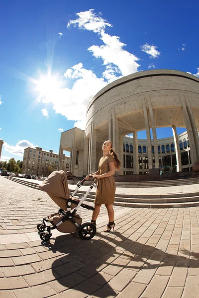 Trendy modern mother on a city street with a pram. Young mother — Stock Photo, Image