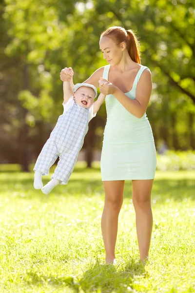 Piccolo bambino carino nel parco estivo con la madre sull'erba. Dolcezza — Foto Stock