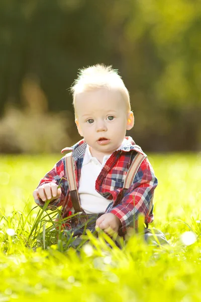 Aranyos kis bébi a parkban, a füvön. édes baba szabadban. mosolygó érzelmi gyerek egy séta. Mosolyogj a gyermek — Stock Fotó