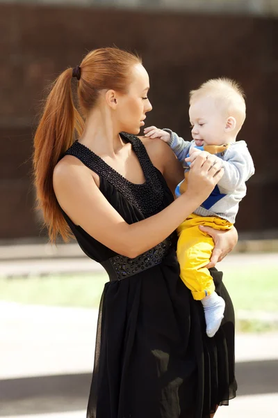 Child in the city. Beautiful young woman with a child in a baby — Stock Photo, Image