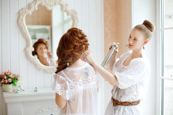 Friseur macht die Braut am Hochzeitstag lizenzfreie Stockbilder