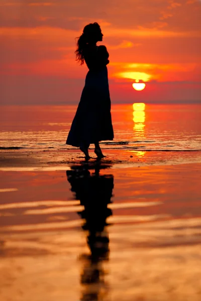 Ευτυχισμένη γυναίκα απολαμβάνοντας το ηλιοβασίλεμα στη θάλασσα. silhouetted έναντι του Σανς Εικόνα Αρχείου