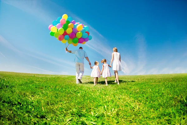 Ευτυχισμένη οικογένεια που κατέχουν το πολύχρωμο Μπαλόνια υπαίθρια. μαμά, ded και δύο Εικόνα Αρχείου