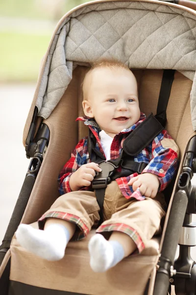 Mooie kleine glimlachende baby in een kinderwagen op de straten Stockafbeelding