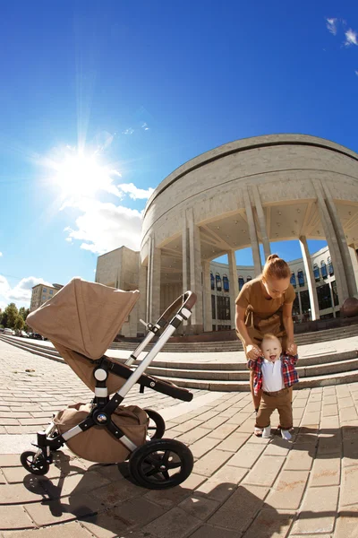 Trendige moderne Mutter auf einer Straße in der Stadt mit Kinderwagen. junge Mutter Stockbild