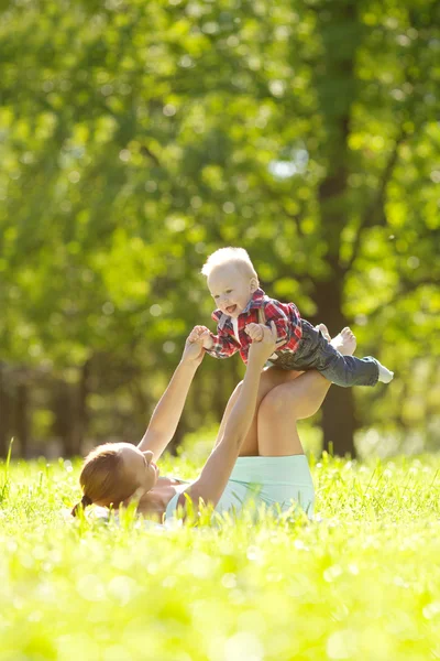 可爱的小宝宝和妈妈在草地上在公园。甜 bab 图库图片