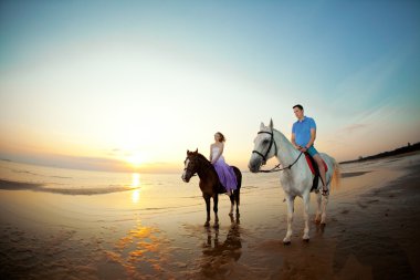 iki bisikletçi sahilde sunset at sırtında. Aşıklar hors binmek
