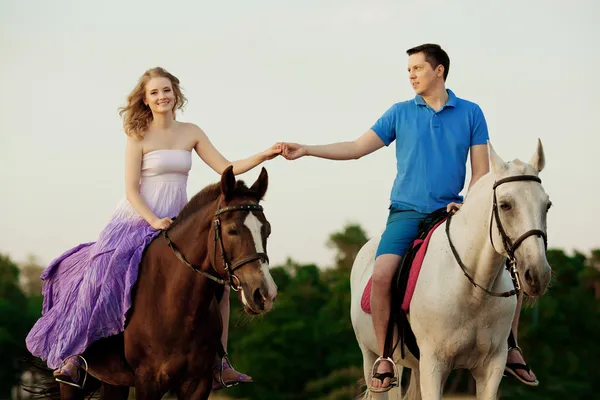 Due cavalieri a cavallo al tramonto sulla spiaggia. Gli amanti cavalcano antipasti — Foto Stock