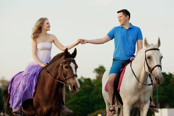 Twee renners te paard bij zonsondergang op het strand. liefhebbers rijden hors — Stockfoto