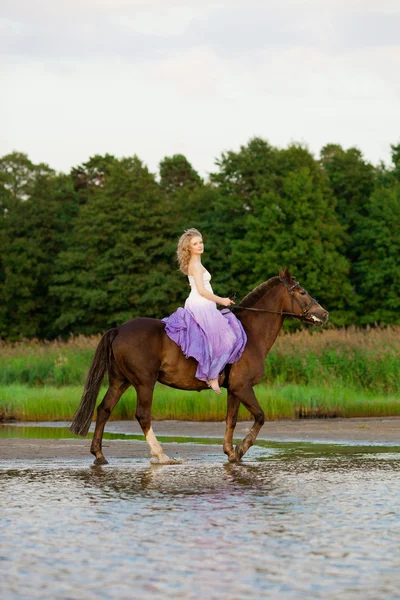 Mulher bonita montando um cavalo ao pôr do sol na praia. Bea jovem — Fotografia de Stock