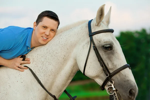 Giovanotto che cavalca un cavallo al tramonto sulla spiaggia. Uomo con un hors — Foto Stock