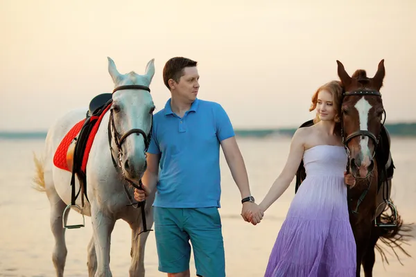 Két lovas lóháton, napnyugtakor a tengerparton. szerelmesek lovagolni hors — Stock Fotó