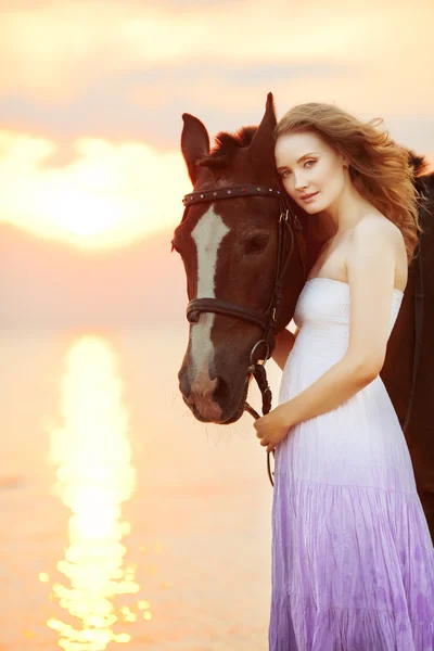 Mulher bonita montando um cavalo ao pôr do sol na praia. Jovem gir — Fotografia de Stock