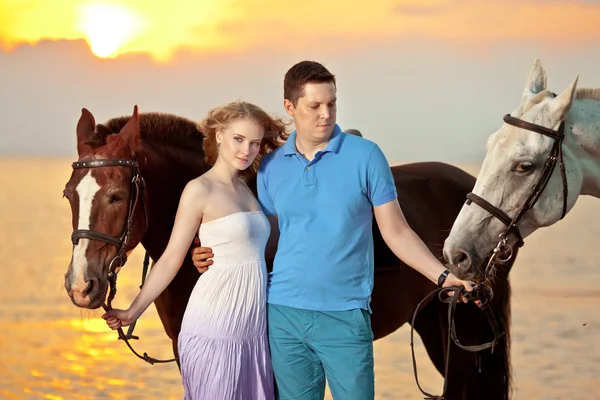 Twee renners te paard bij zonsondergang op het strand. liefhebbers rijden hors — Stockfoto