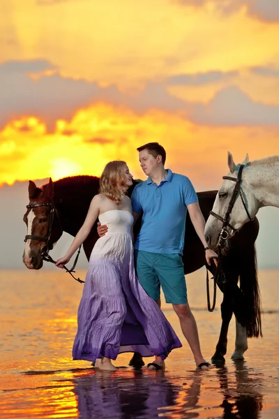 Deux cavaliers à cheval au coucher du soleil sur la plage. Lovers ride hors — Photo