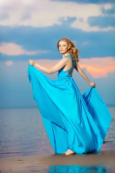 Femme de luxe dans une longue robe de soirée bleue sur la plage. Beauté — Photo