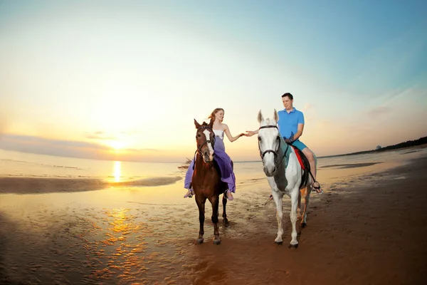 Two riders on horseback at sunset on the beach. Lovers ride hors Stock Photo
