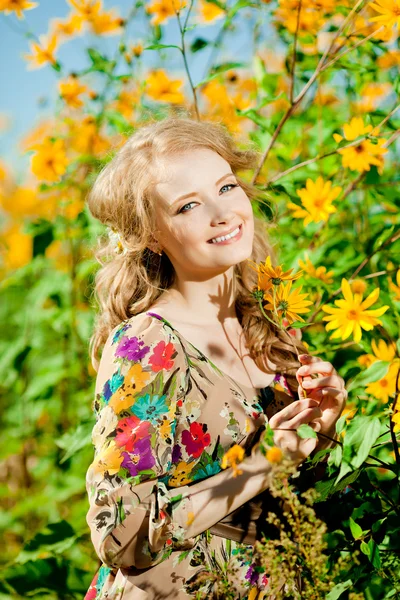 Νεαρή όμορφη χαμογελαστό γυναίκα στην ο ανθισμένος κήπος με λουλούδι — Φωτογραφία Αρχείου