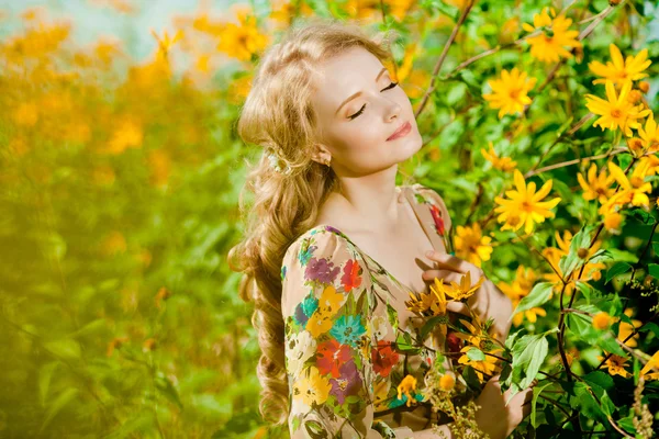 Молода красива усміхнена жінка в квітучому саду з квіткою — стокове фото