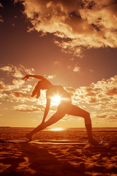 Молодая красивая стройная женщина силуэт практикует йогу на Beac — стоковое фото