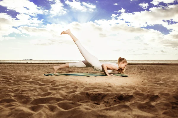 Jovem bela mulher magra pratica ioga na praia em sunris — Fotografia de Stock