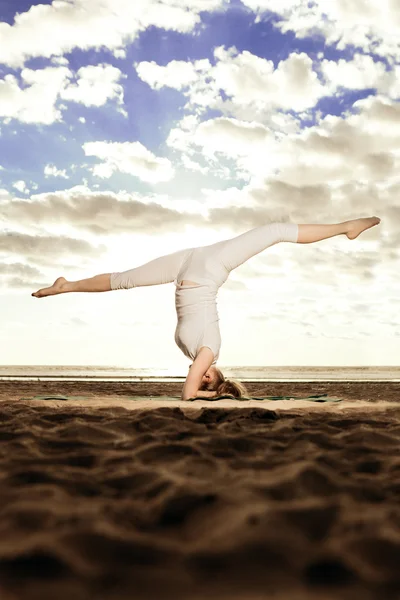 Joven hermosa mujer delgada practica yoga en la playa al atardecer —  Fotos de Stock