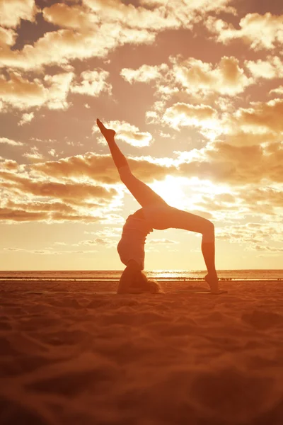 Junge schöne schlanke Frau Silhouette übt Yoga auf dem Beac — Stockfoto