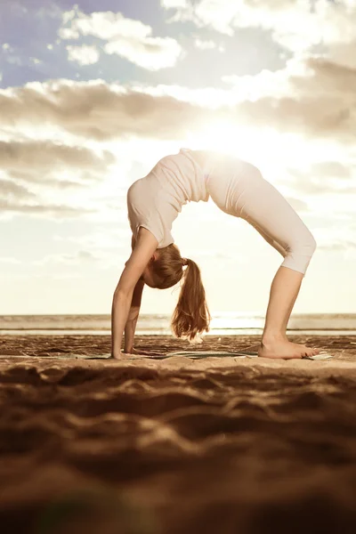 Ung vacker smal kvinna praxis yoga på stranden vid sunris — Stockfoto