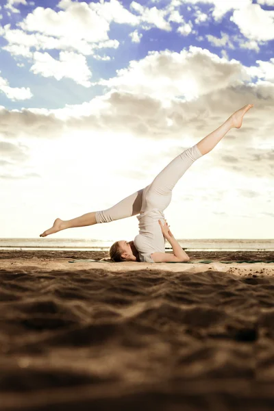 Ung vacker smal kvinna praxis yoga på stranden vid sunris — Stockfoto