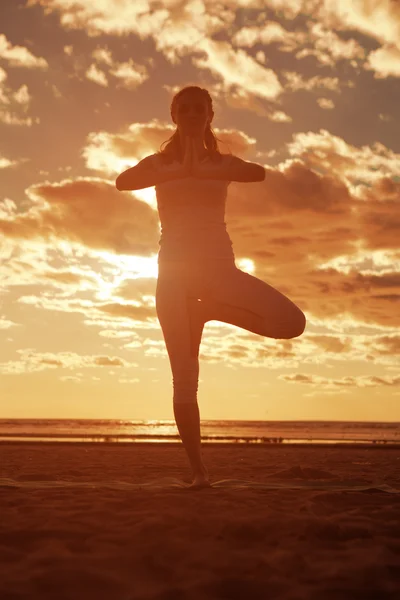 Young beautiful slim woman silhouette practices yoga on the beac — Stock Photo, Image