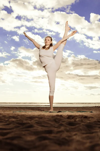 Jonge mooie slanke vrouw praktijken yoga op het strand bij zonsondergang — Stockfoto