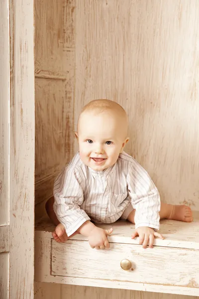 Gyönyörű kisbaba ült a szekrényben. mosolygó gyermek, és — Stock Fotó