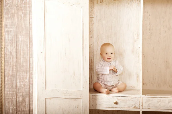 Piękne małe dziecko siedzi w szafie. uśmiechający się dziecko i — Zdjęcie stockowe