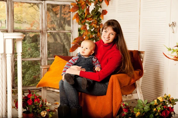 Schöne Frau mit Kind auf der Veranda mit Kürbissen au — Stockfoto