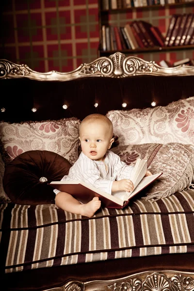 Malé dítě v interiéru, čtení knihy. usmívající se dítě v Stock Obrázky